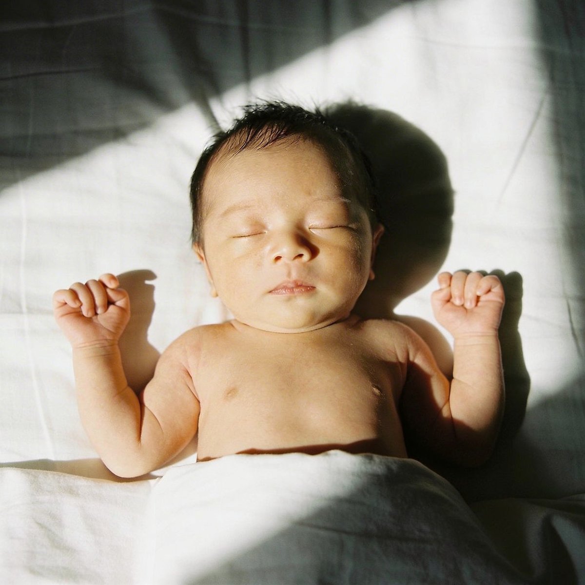Baby photographed with soft natural light near a window at a 45-degree angle